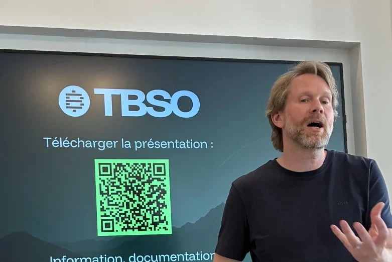 Eric Larchevêque en costume, portrait en gros plan, avec un fond flou évoquant le bitcoin et la tech