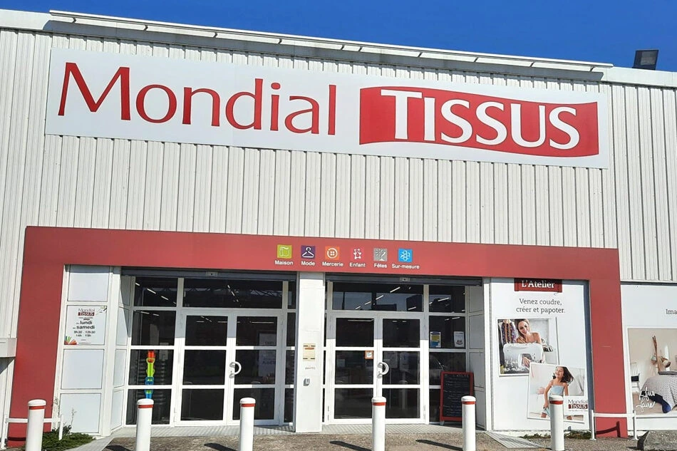 Façade de la boutique Mondial Tissus à Paris 14e, vitrine avec rouleaux de tissus et enseigne visible