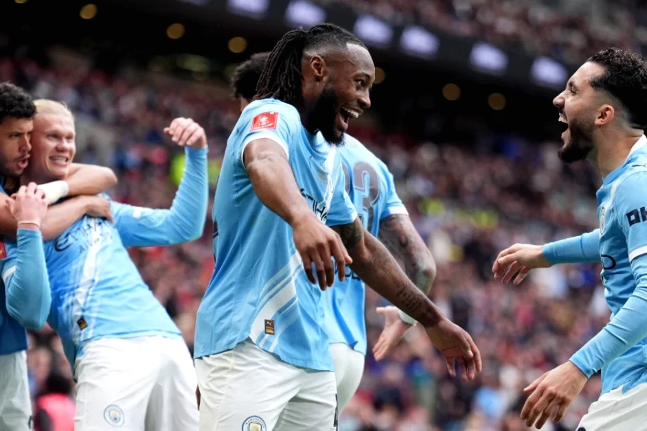 Joueur de Manchester City brandissant la FA Cup, entouré de coéquipiers en célébration sur la pelouse