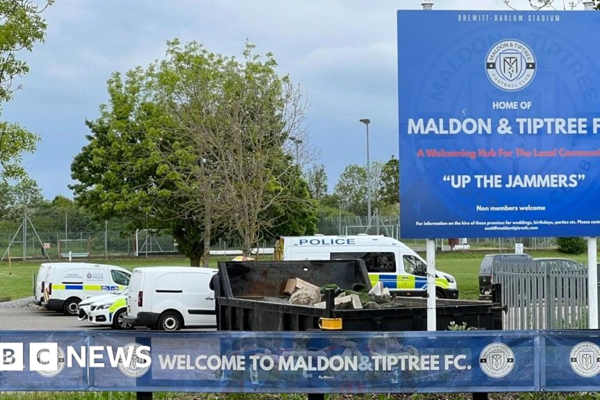 Joueurs de Maldon and Tiptree FC sur le terrain, en maillots jaunes et bleus, près du but.