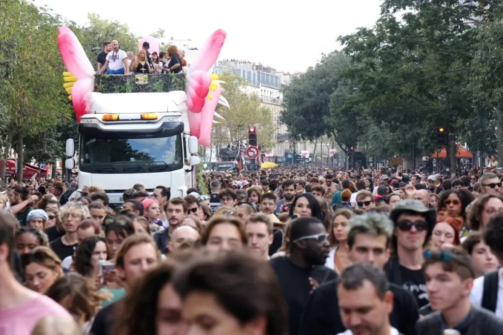 La Techno Parade à Paris : foule dense dans la rue, chars sonorisés et drapeaux sous un ciel bleu