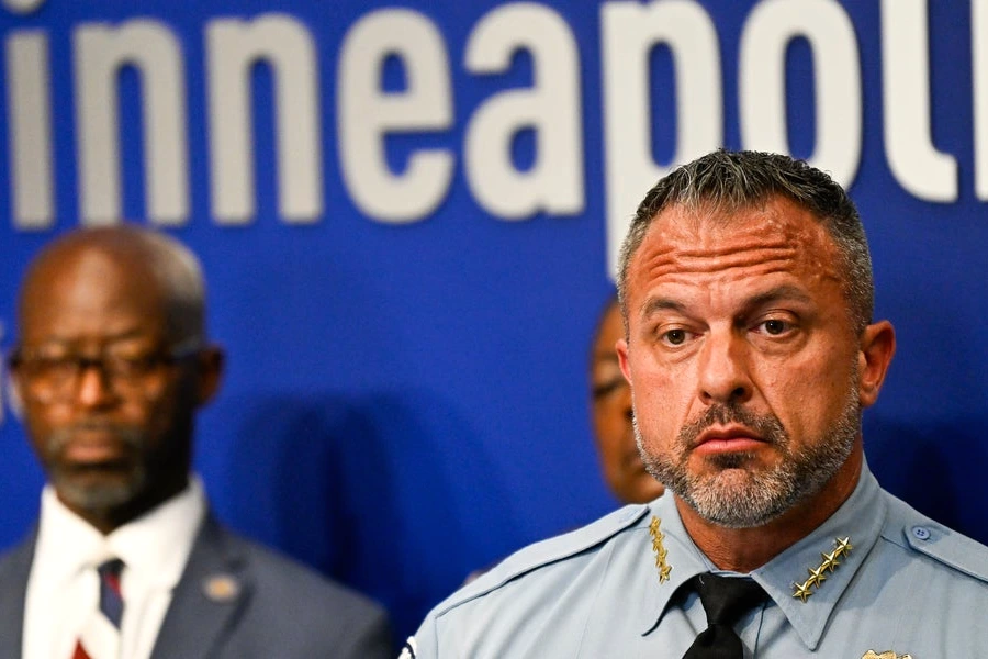Le chef de la police de Minneapolis en uniforme, debout devant un pupitre lors d’une conférence de presse.