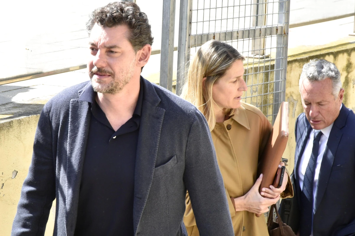 Le fils du fondateur de Mango escorté par la police devant un bâtiment, menottes aux poignets