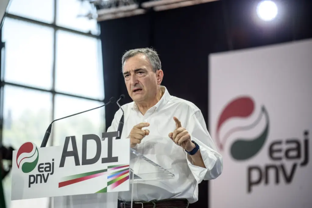 Le leader du PNV s’exprime au micro devant des journalistes, avec Pedro Sánchez en arrière-plan.