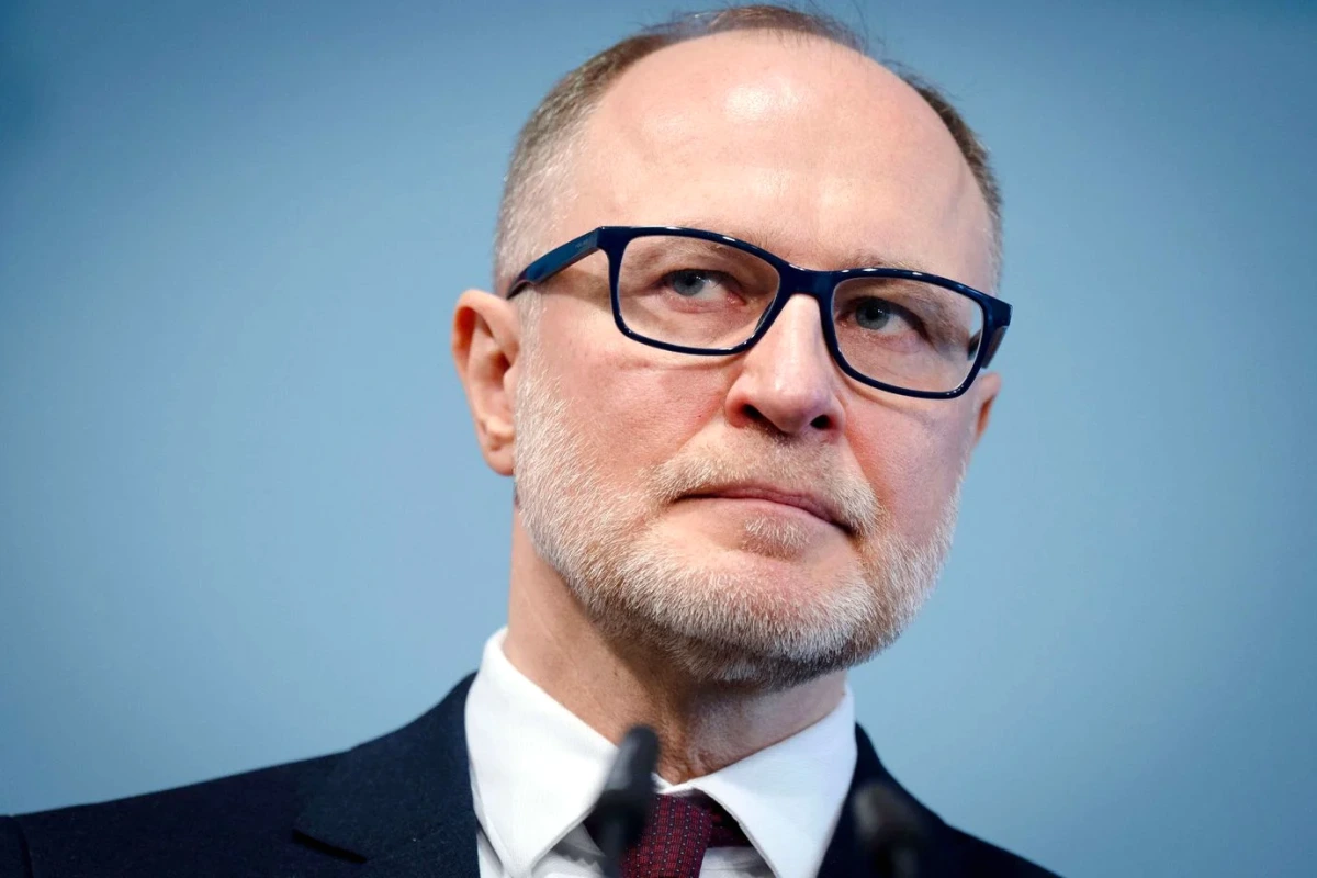 Le ministre letton de la Défense s’exprime devant des drapeaux, micros et journalistes en arrière-plan