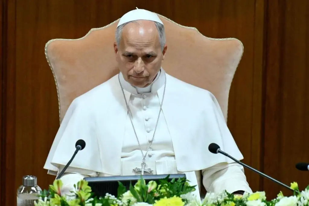 Le pape Léon XIV salue la foule depuis un balcon du Vatican, micro à la main, drapeaux en bas.