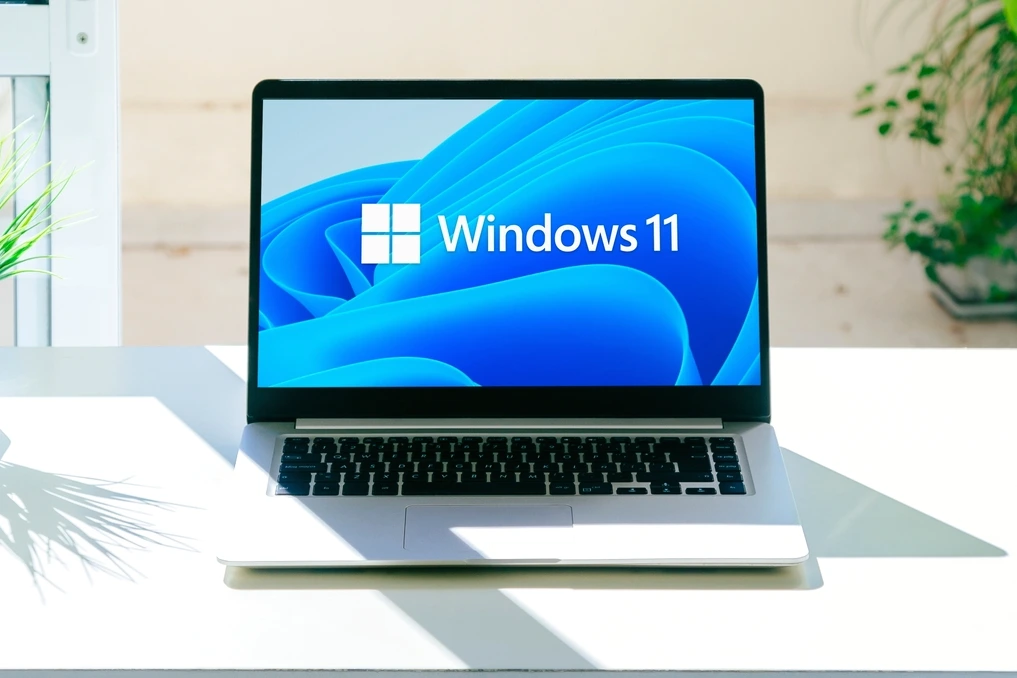 Logo Windows 11 sur un écran d’ordinateur, avec icônes audio et indicateurs de performances en arrière-plan