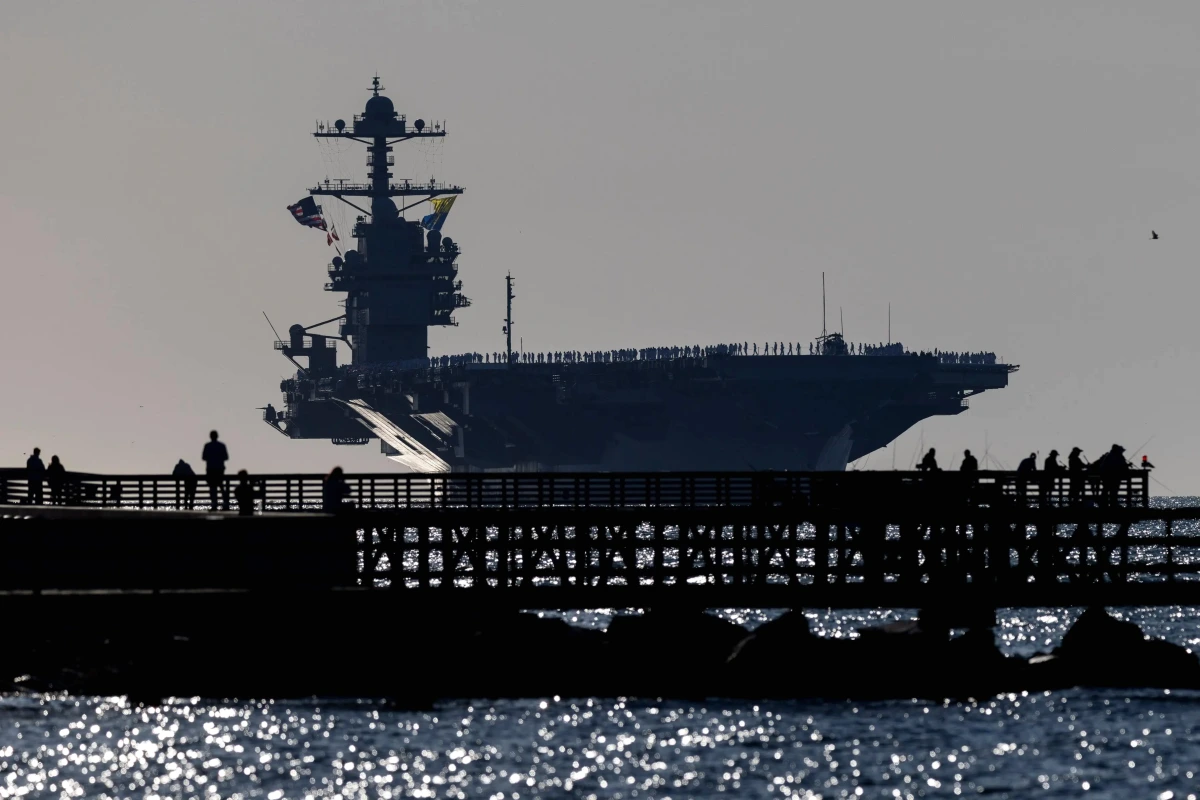 L’USS Ford navigue en mer au coucher du soleil, porte-avions et avions alignés sur le pont