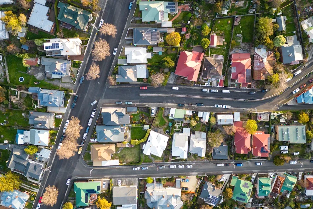 Maisons en banlieue australienne avec drapeau de l’Australie, sous un ciel bleu, devant une agence immobilière