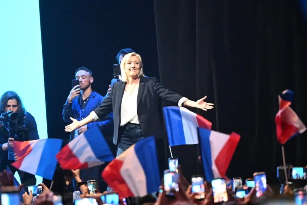 Marine Le Pen et Jordan Bardella sur scène à Mâcon, devant une foule et des drapeaux du RN