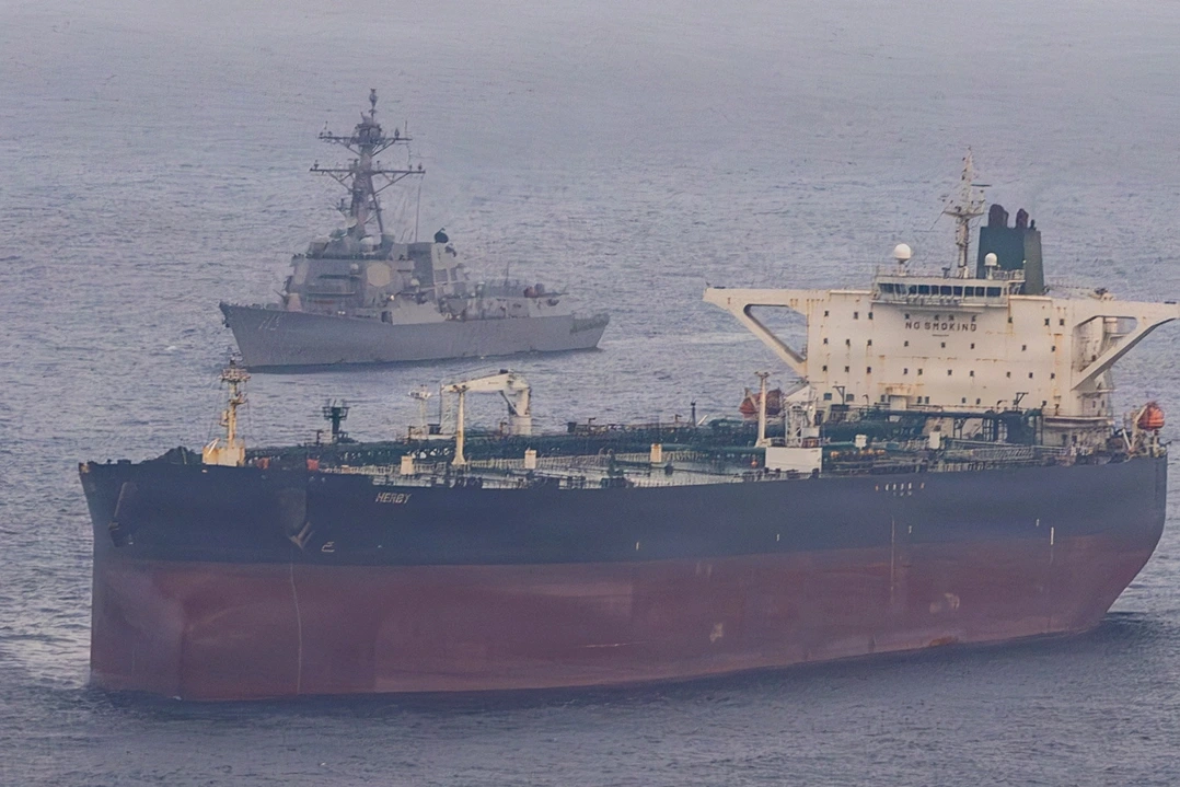 Navires militaires dans le détroit d’Ormuz, mer agitée et fumée au loin sous un ciel gris