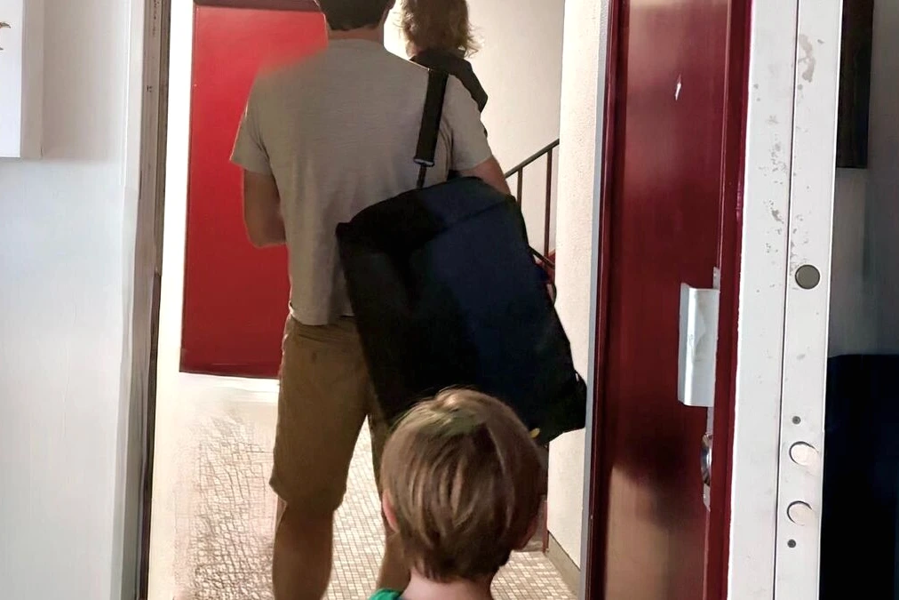 Parents séparés avec valises devant un immeuble parisien, cherchant un logement après la séparation