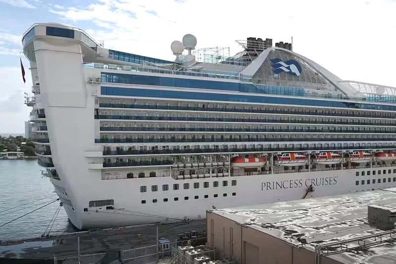 Passagers sur un bateau de croisière, avec un panneau d’avertissement sur une épidémie de norovirus