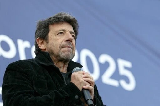 Patrick Bruel sur scène à Paris, devant un décor de théâtre, saluant le public sous les projecteurs