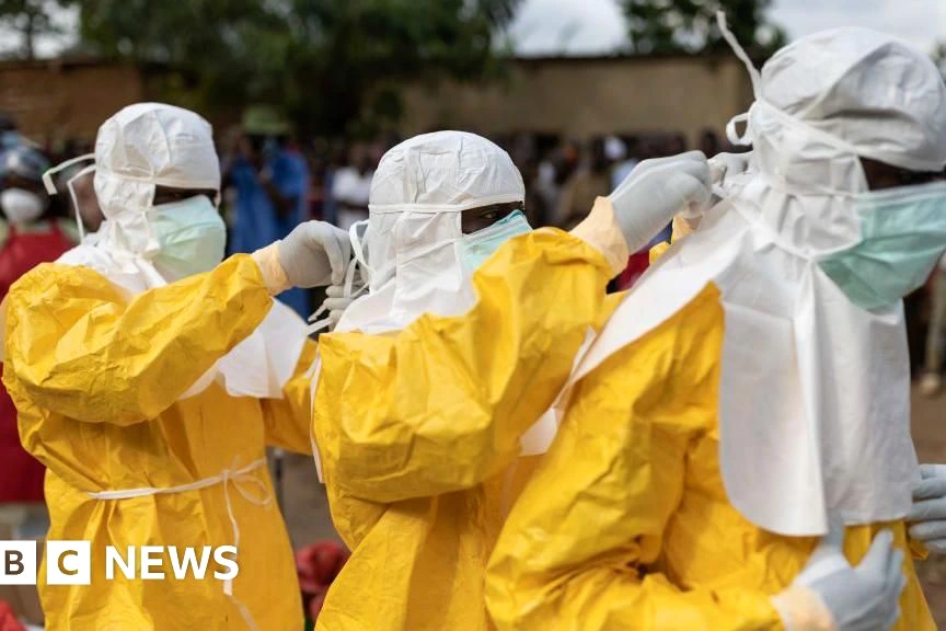 Personnel médical en RDC en tenue de protection, désinfectant une zone lors de l’épidémie d’Ebola