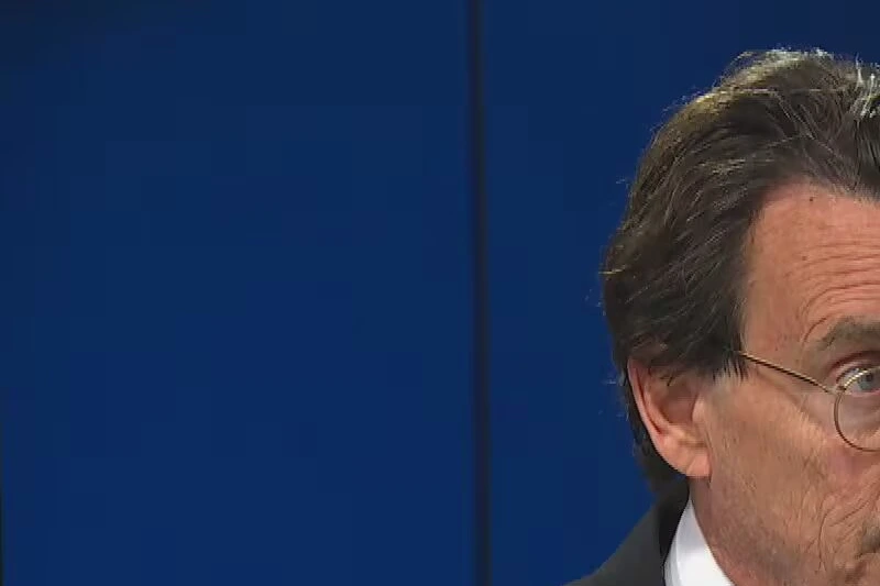 Pierre Karl Péladeau en costume, parlant au micro lors d’une conférence de presse devant des caméras