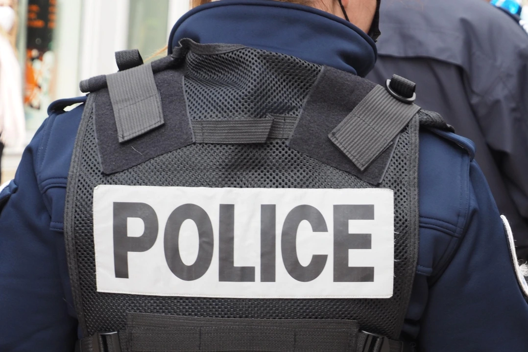 Policier près de Paris, arme au poing, face à un homme tenant des couteaux dans une rue bouclée