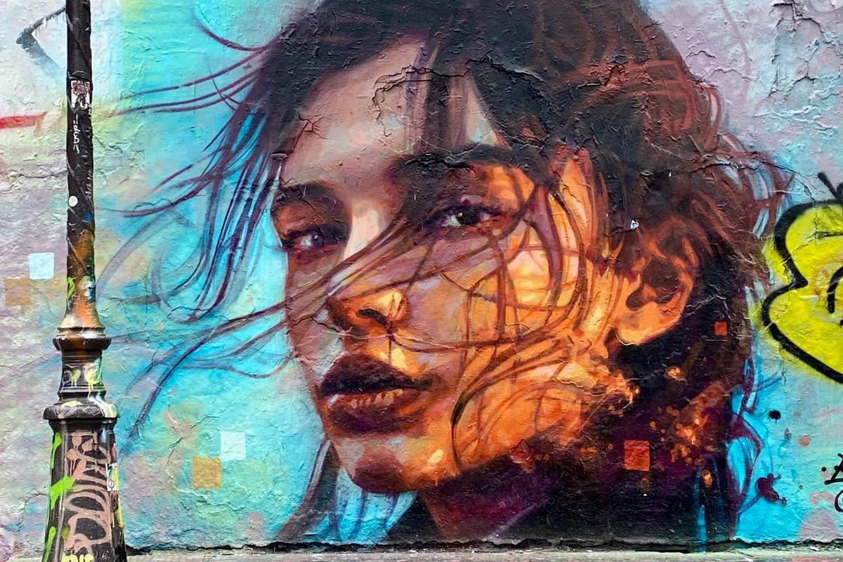 Portrait féminin de street art près du canal Saint-Martin, visage coloré peint sur un mur parisien