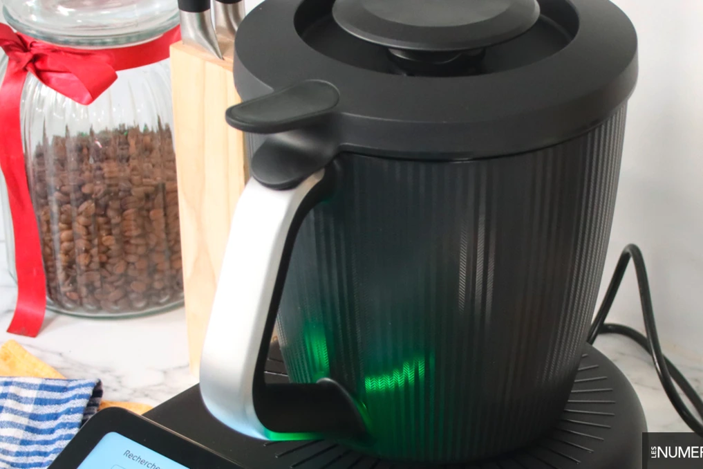 Robot cuiseur multifonctions argenté sur un plan de travail, bol inox et écran tactile allumé, accessoires à côté