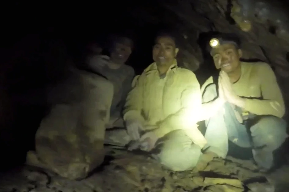 Secouristes au Laos devant l’entrée d’une grotte inondée, éclairée par des lampes, lors des recherches.