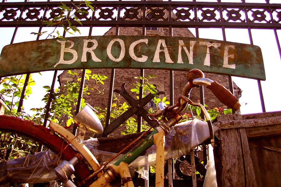 Stands de vide-greniers et brocantes à Paris, tables d’objets vintage et foule dans une rue animée.
