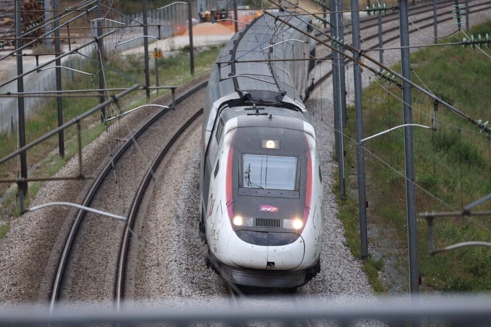 TGV à l’arrêt en gare, voyageurs attendant sur le quai, panneau d’affichage indiquant un retard de 7 heures