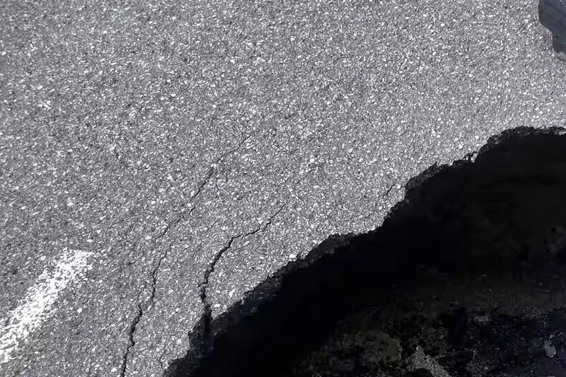 Un énorme trou sur la route 117, section fermée avec cônes orange et barrières de sécurité
