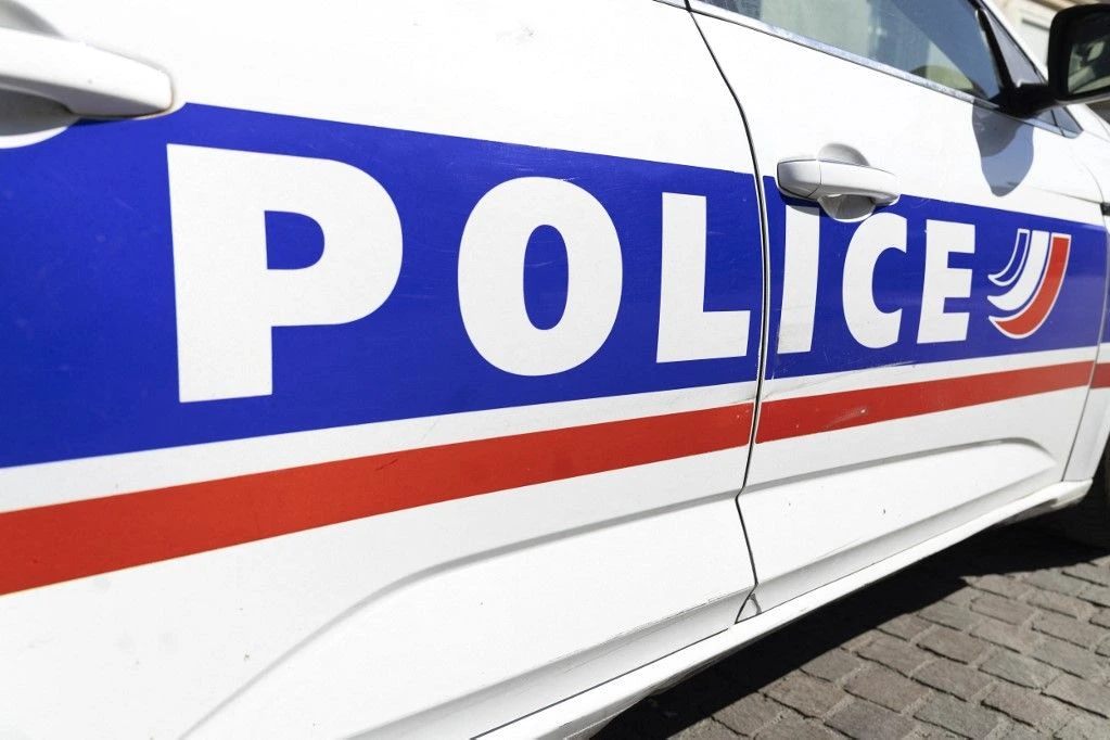 Un homme interpellé par des policiers devant des toilettes publiques à Paris, ruban de sécurité en arrière-plan