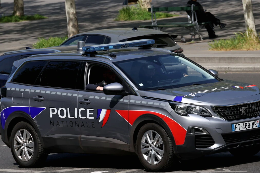 Voitures de police et ruban de sécurité devant un immeuble du XXe à Paris après un homme tué
