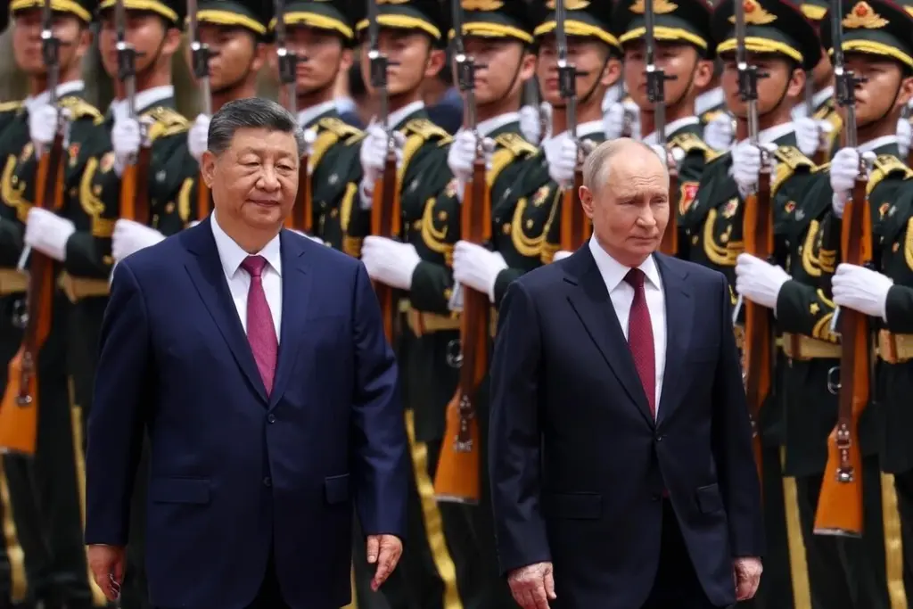 Xi Jinping serre la main de Vladimir Poutine lors d’une rencontre officielle à Pékin, devant des drapeaux.