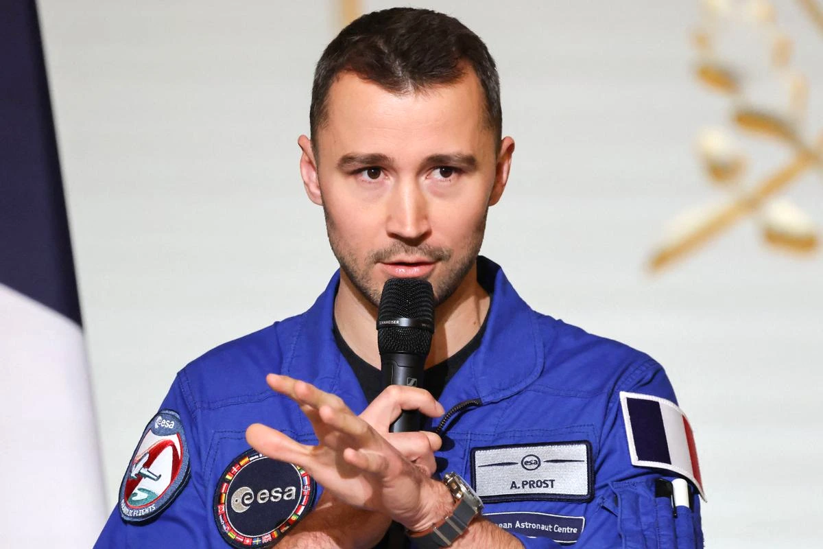 Arnaud Prost en combinaison d’astronaute, casque sous le bras, devant une fusée sur le pas de tir