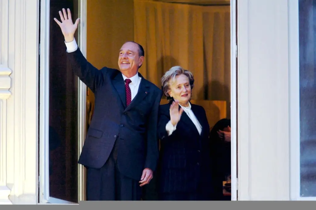 Bernadette Chirac souriante lors d’un événement officiel à Paris, en tenue élégante, devant un bâtiment historique
