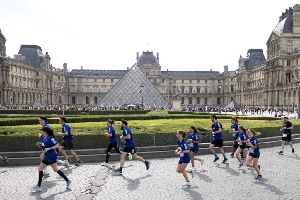 Coureurs du 10K de Paris 2026 franchissant la ligne d’arrivée, chronomètre et foule en arrière-plan