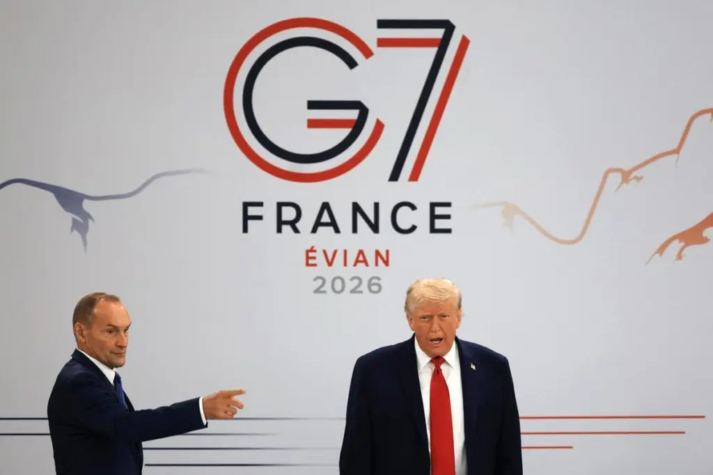 Donald Trump au sommet du G7 à Évian, debout devant des drapeaux, s’adressant aux dirigeants.