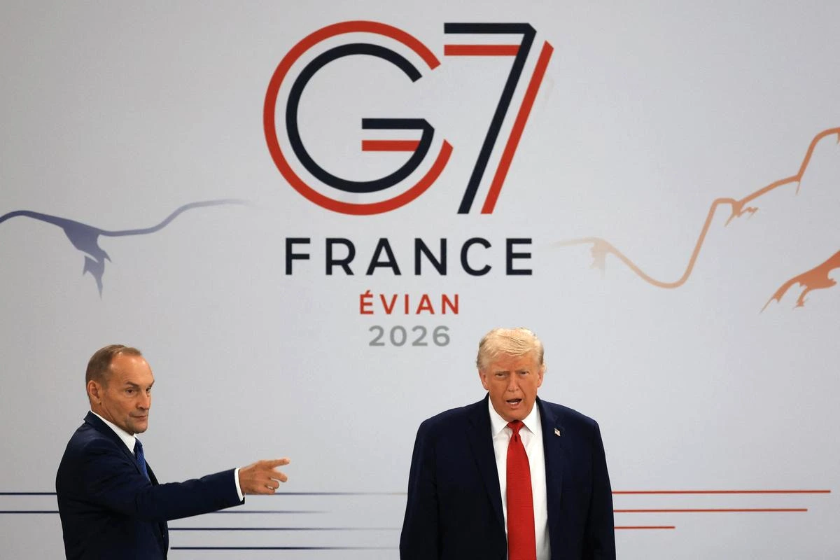 Donald Trump au sommet du G7 à Évian, debout devant des drapeaux, s’adressant aux dirigeants.