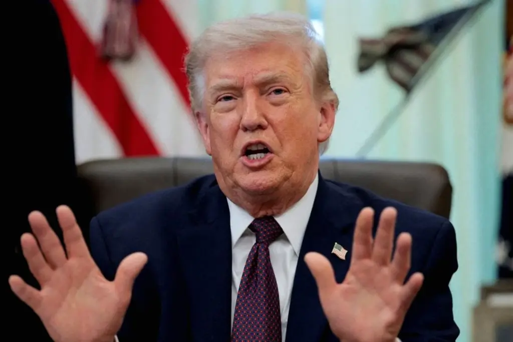 Donald Trump s’exprime devant des journalistes, drapeaux américains en arrière-plan, micro au premier plan