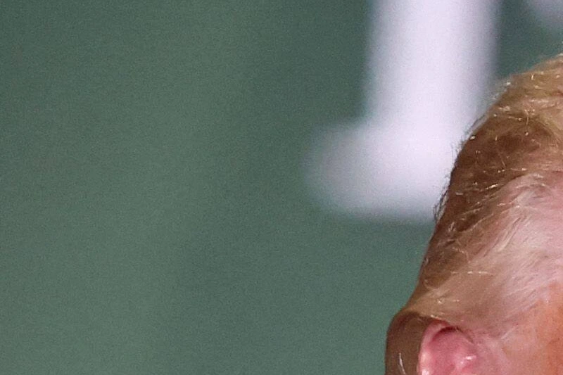 Donald Trump, visage fermé, parle à des journalistes devant des micros lors d’une entrevue interrompue