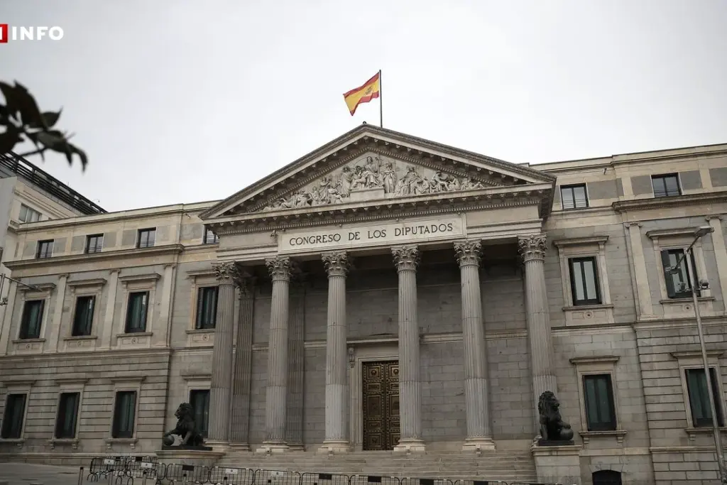 Drapeau espagnol flottant devant un bâtiment officiel, avec silhouettes d’enfants en arrière-plan