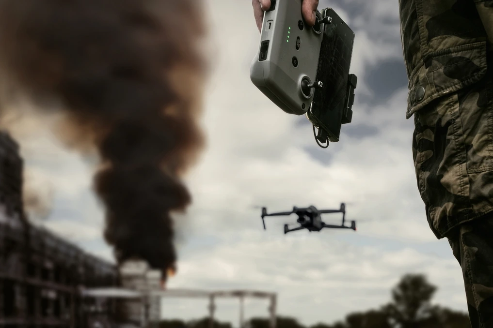Drone autonome dopé à l’IA survolant un champ de bataille, soldats au sol et explosions en arrière-plan