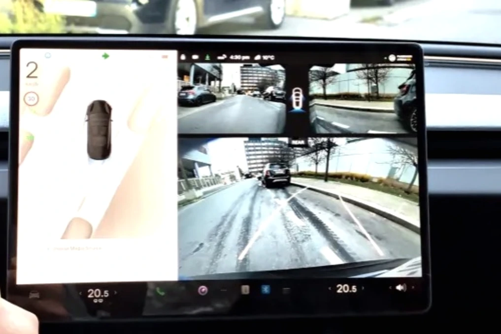 Elon Musk sur scène devant un écran Tesla, avec une voiture en arrière-plan et le logo FSD affiché