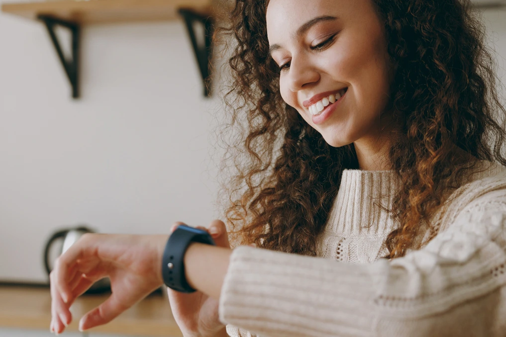 Montre connectée et tracker d’activités posés côte à côte sur une table, avec étiquettes de prix sous 100 €