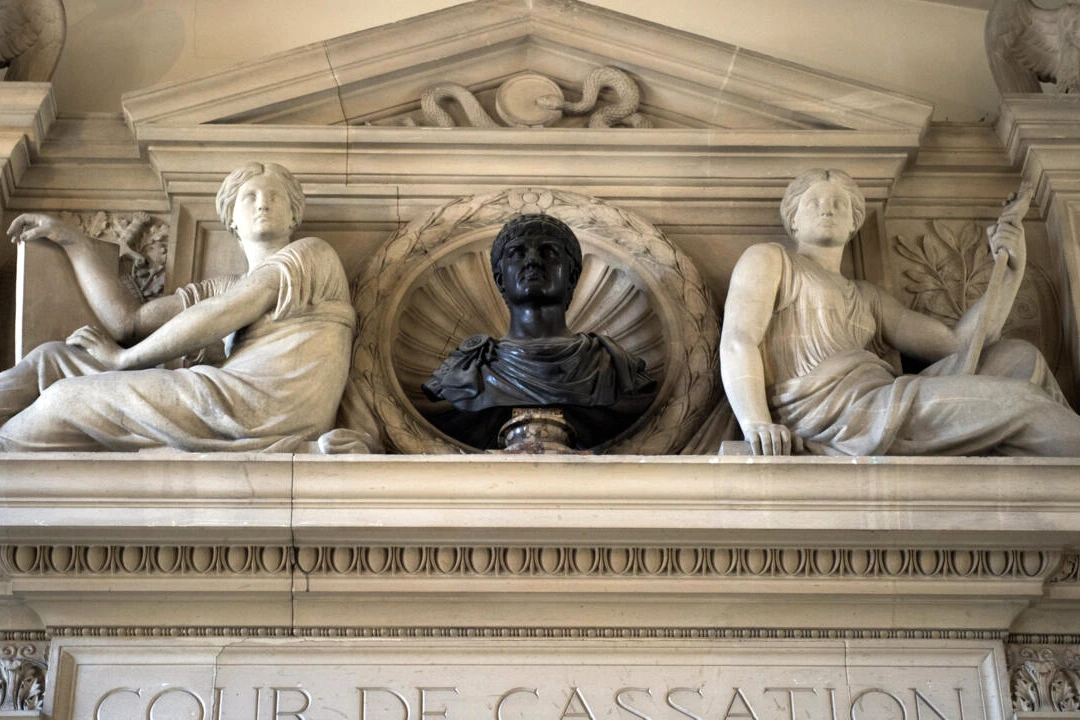 Nahel commémoré par des fleurs et bougies au pied d’un portrait, devant un bâtiment judiciaire en arrière-plan