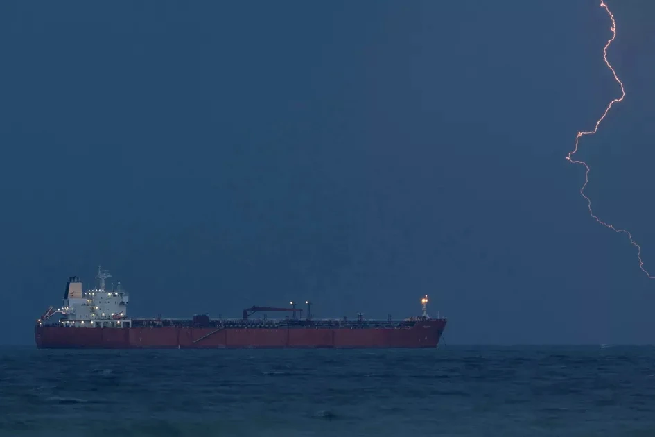 Navire pétrolier immobilisé en mer, avec un bâtiment militaire américain à proximité, sous ciel gris