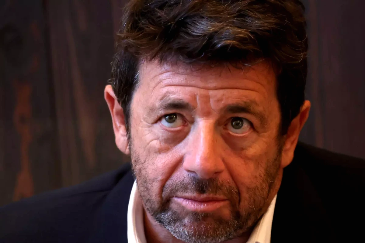 Patrick Bruel en gros plan, visage sérieux, devant un fond sombre lors d’un événement public