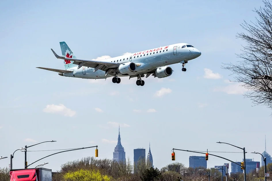 Pilote d’Air Canada en uniforme devant un avion de ligne, sur le tarmac de l’aéroport.