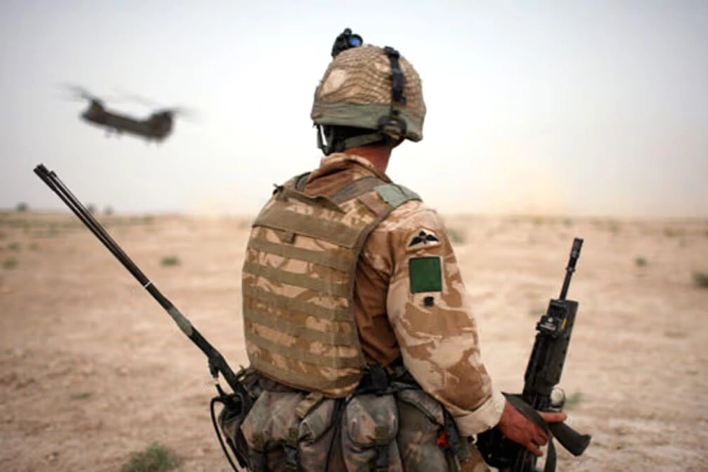 Soldats britanniques en tenue de combat près de véhicules militaires sur un terrain d'entraînement en Irak