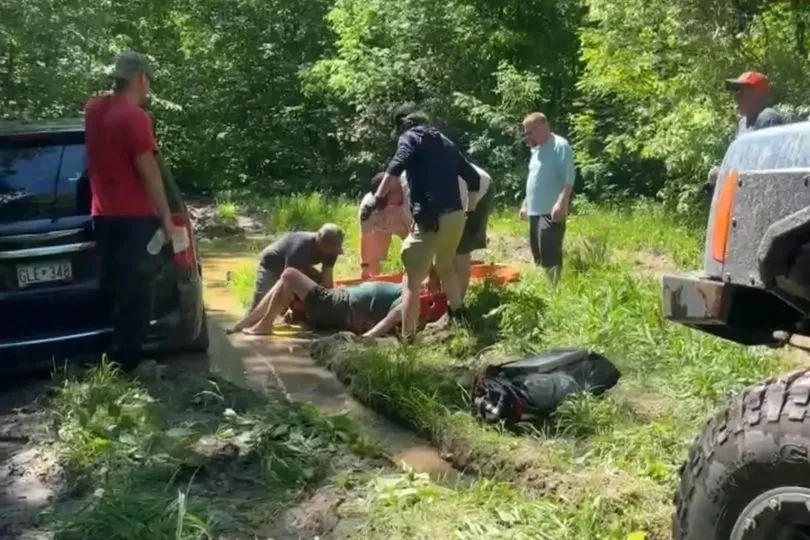 Une femme du Minnesota secourue, couverte de boue, entourée de sauveteurs près d’un terrain marécageux.